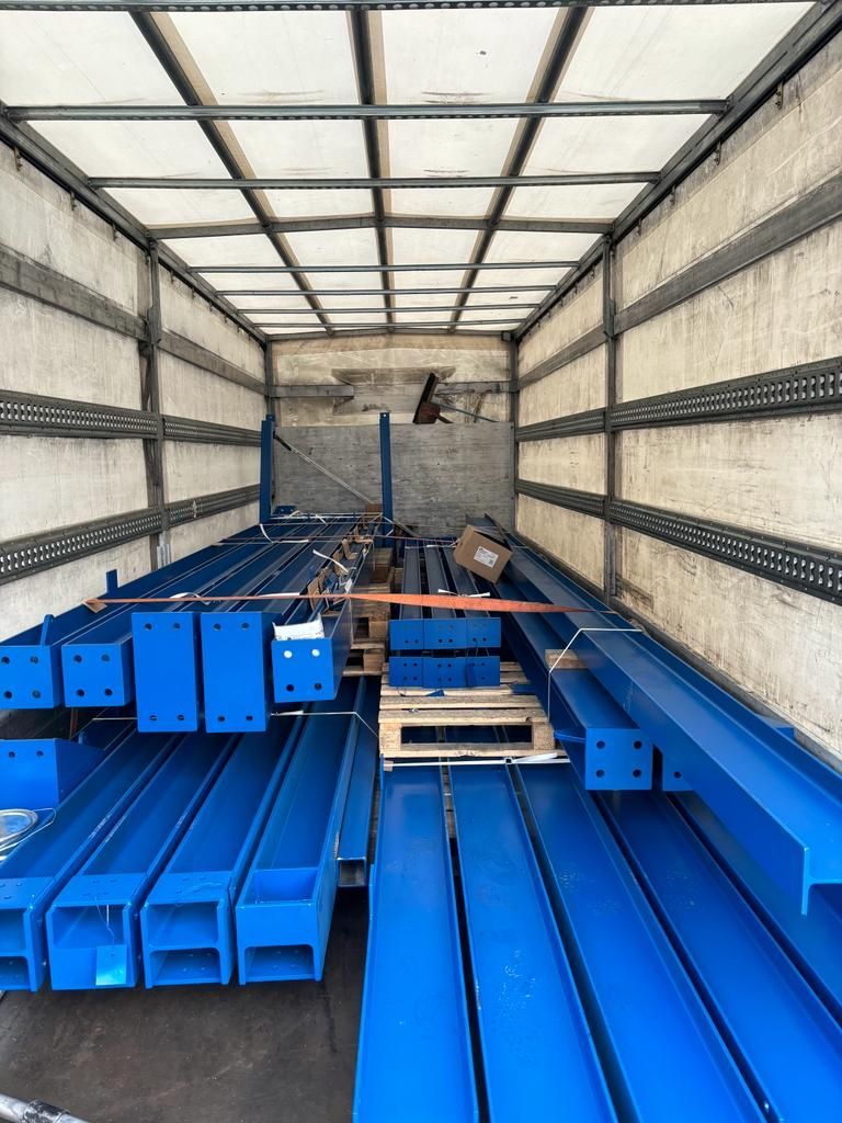 Im Inneren eines Lastwagens sind blaue Metallträger und -teile gestapelt und für den Transport bereit.