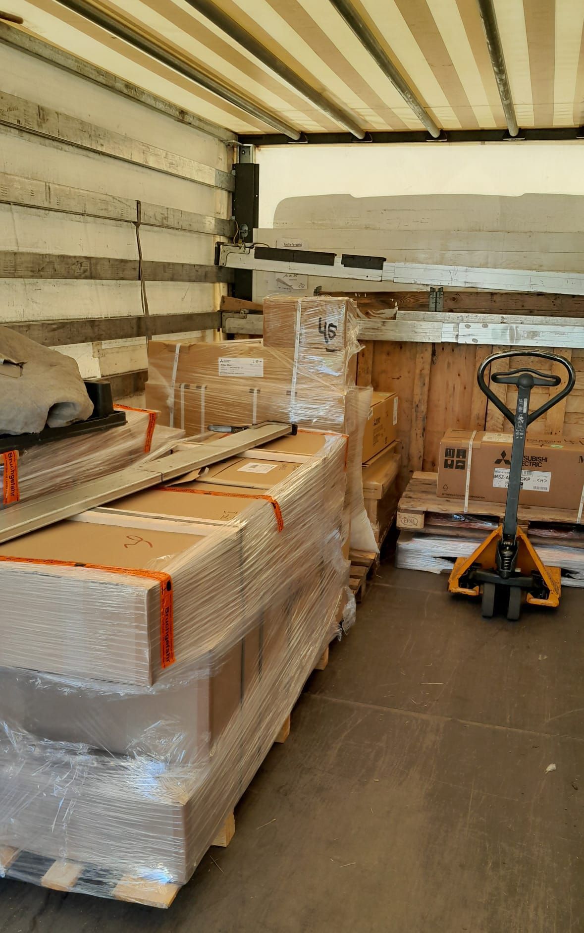Im Inneren eines Lastwagens: Kisten auf Paletten und ein Hubwagen.