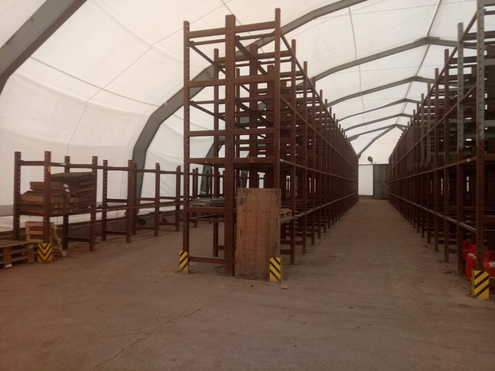 Lagerhalleninnenraum mit Metallregalen unter einem weißen Zeltdach.