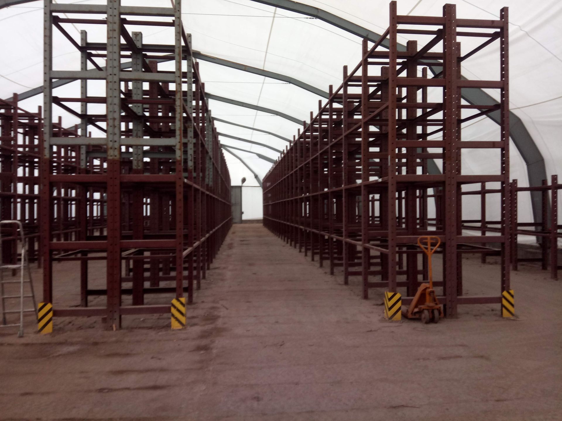 Lagerhalleninnenraum mit Metallregalen unter einem weißen Stoffdach.