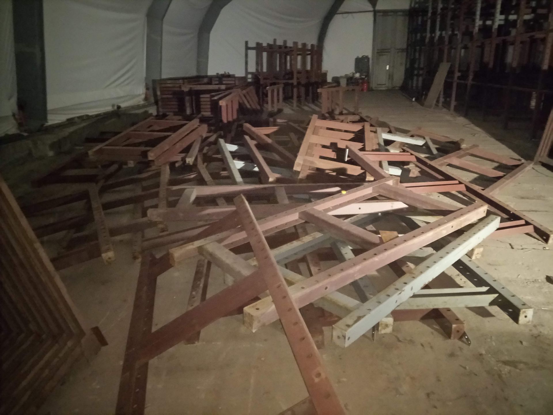 Ein Haufen zerlegter Holzrahmen in einem schwach beleuchteten Lagerhaus.