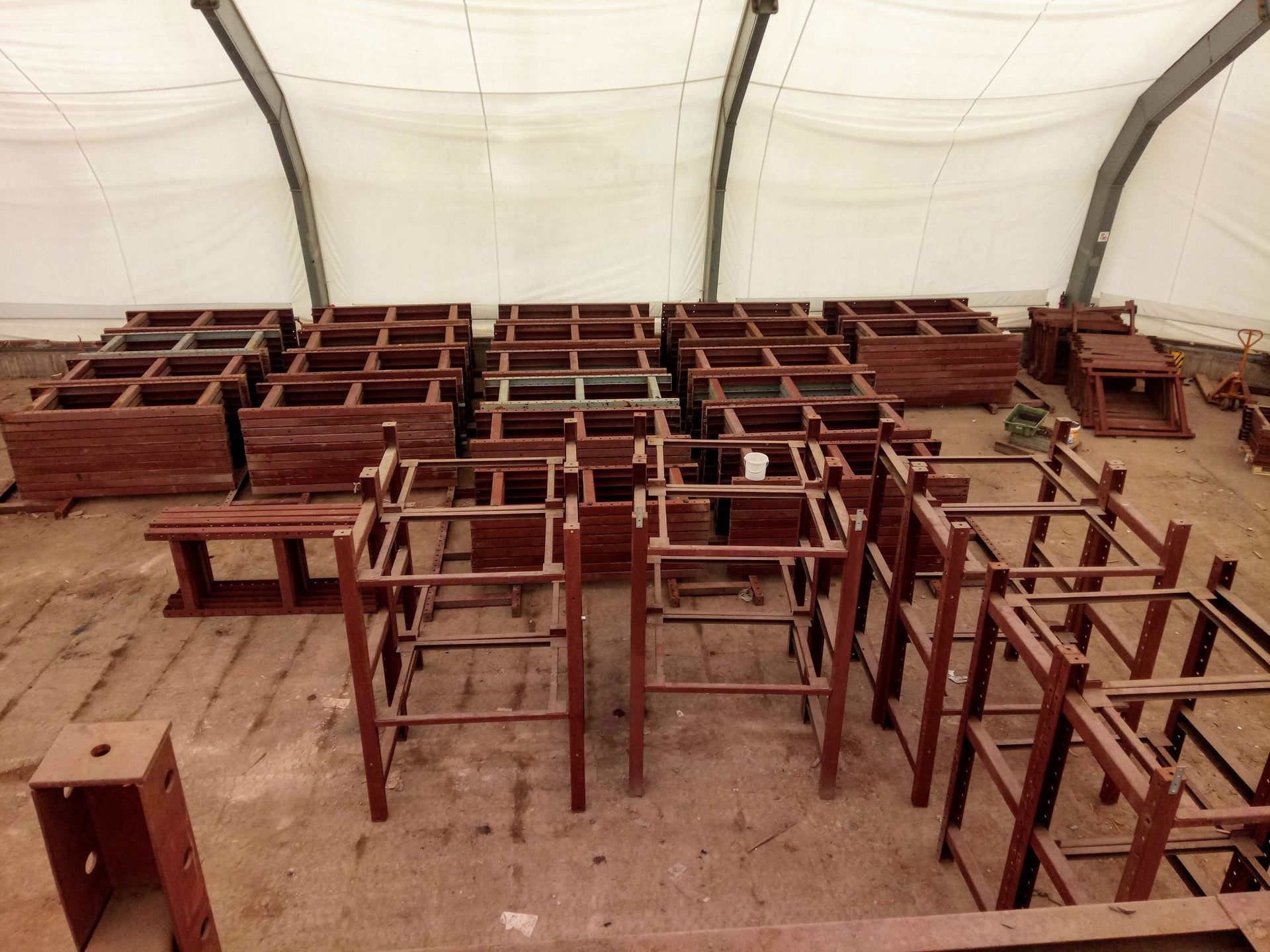 Holzrahmen, vermutlich Möbelteile, die in einer zeltartigen Struktur mit weißer Decke angeordnet sind.