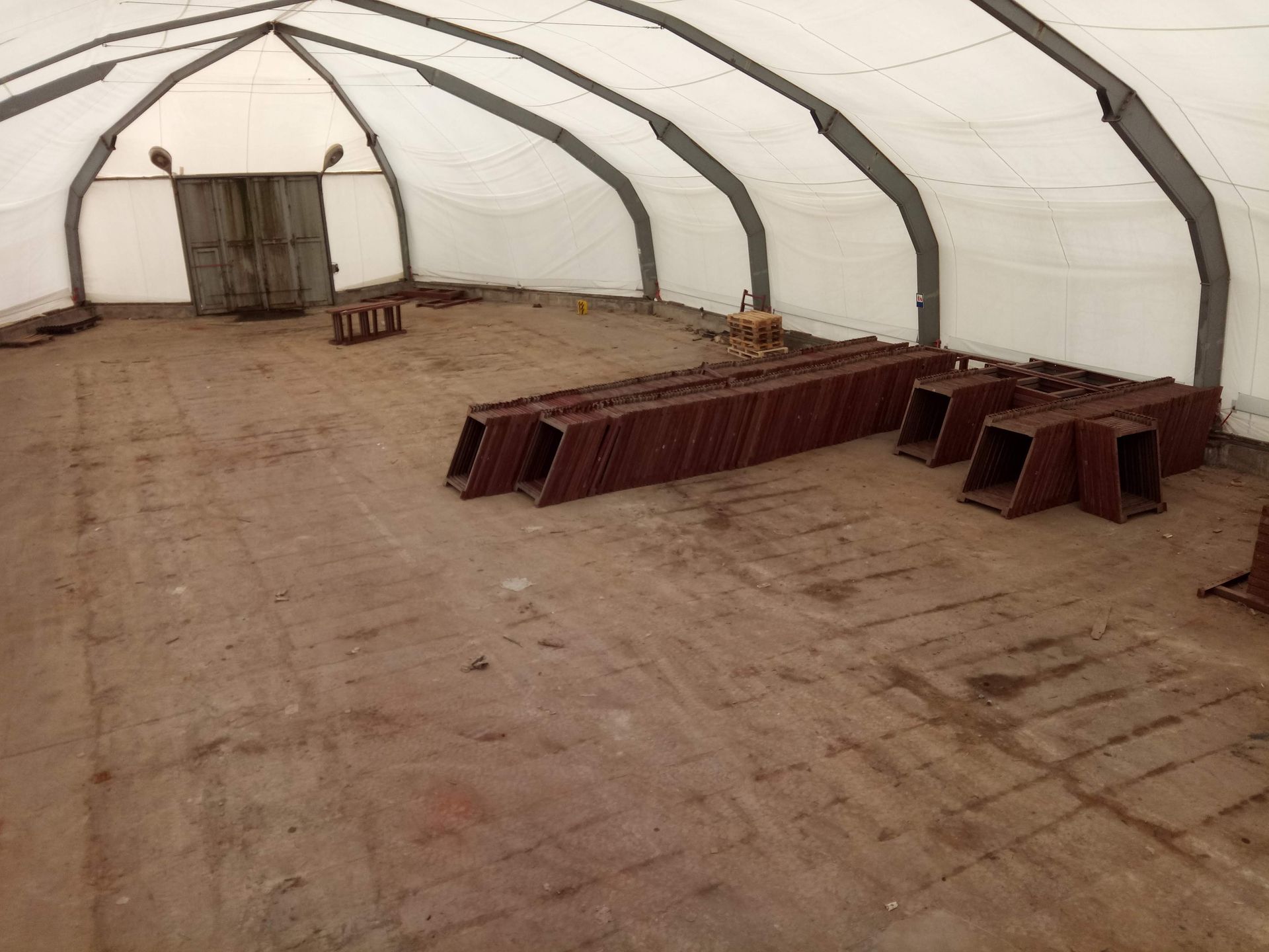 Braunes Inneres eines weißen Zeltes mit Metallträgern und einer Holztür.