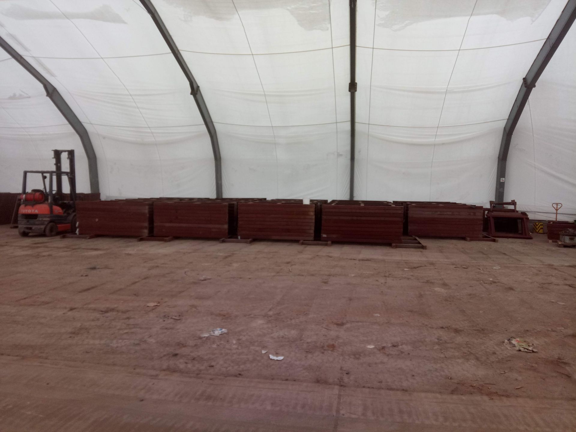 Innenansicht eines Lagergebäudes mit roten Materialien und einem Gabelstapler.