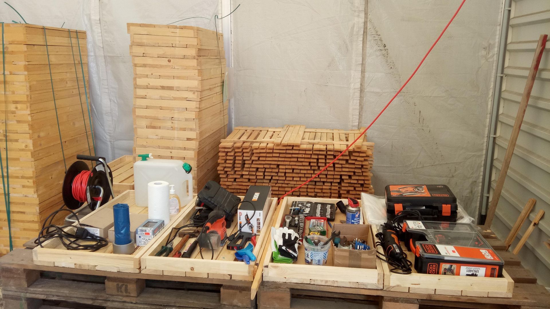 Holzpaletten zur Aufbewahrung von Werkzeugen und Materialien in einem Lagerbereich.