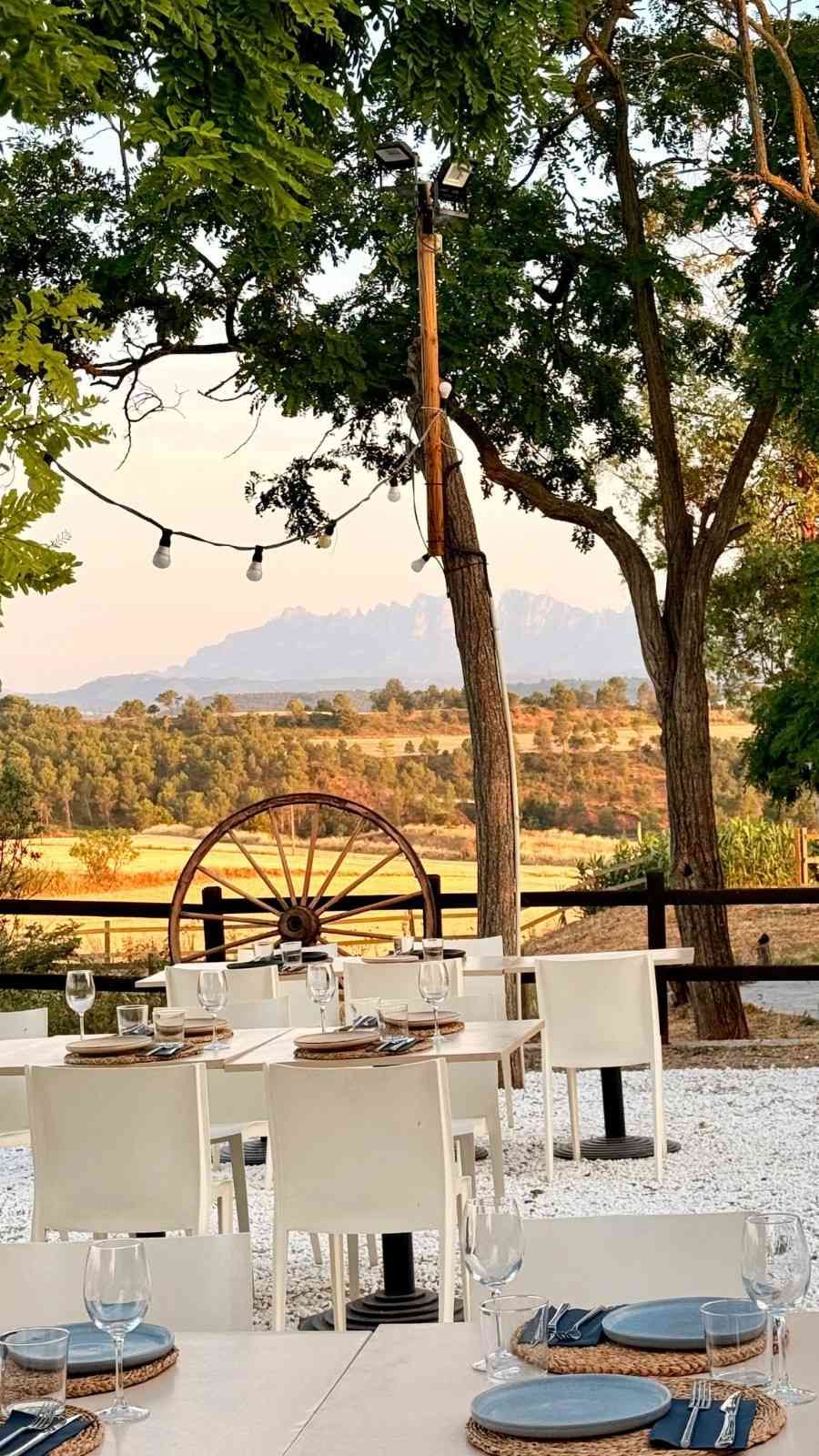 Mesas y sillas de comedor al aire libre con vistas a un pintoresco lago y colinas al atardecer.