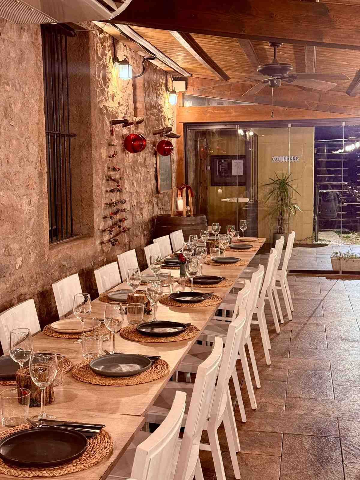 Mesa de comedor rústica larga, con platos y vasos, en un acogedor restaurante con paredes de ladrillo.