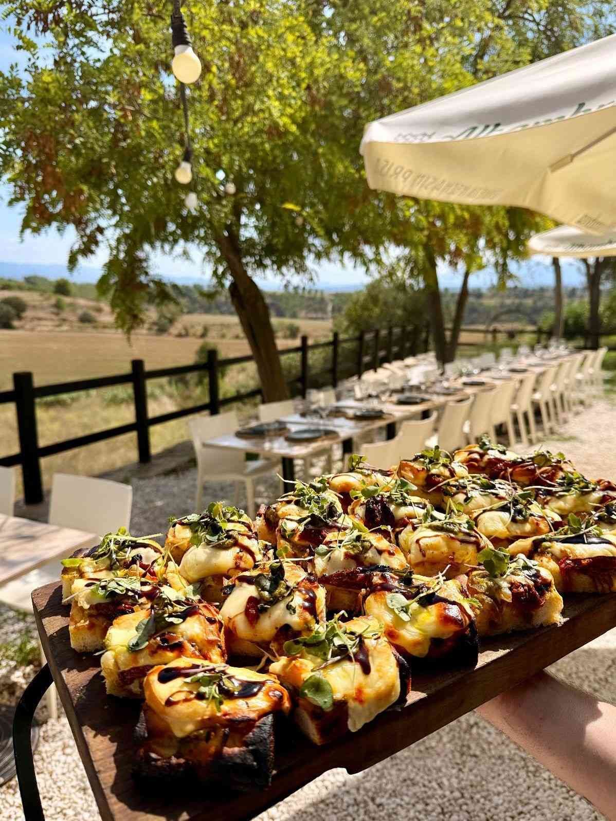 Bandeja de aperitivos a la parrilla con hierbas aromáticas, servida al aire libre junto a un patio soleado