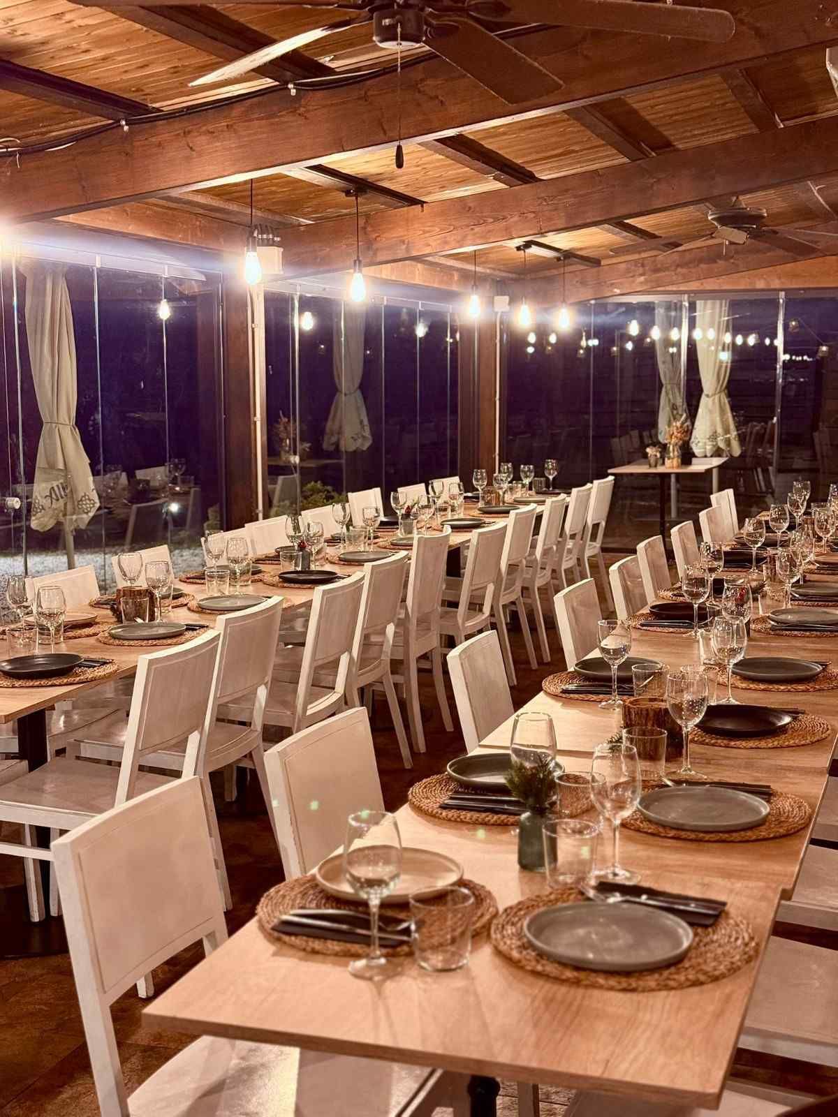 Elegante montaje para banquetes al aire libre con largas mesas de madera, sillas blancas