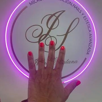 La mano de una mujer con uñas rojas está parada frente a un letrero de neón.