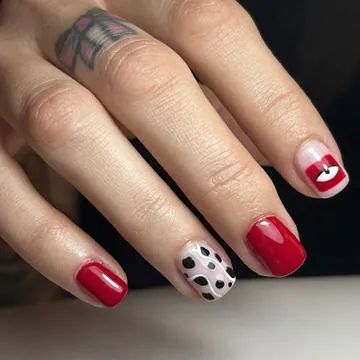 Las uñas de una mujer están pintadas de rojo y blanco con un estampado dálmata.