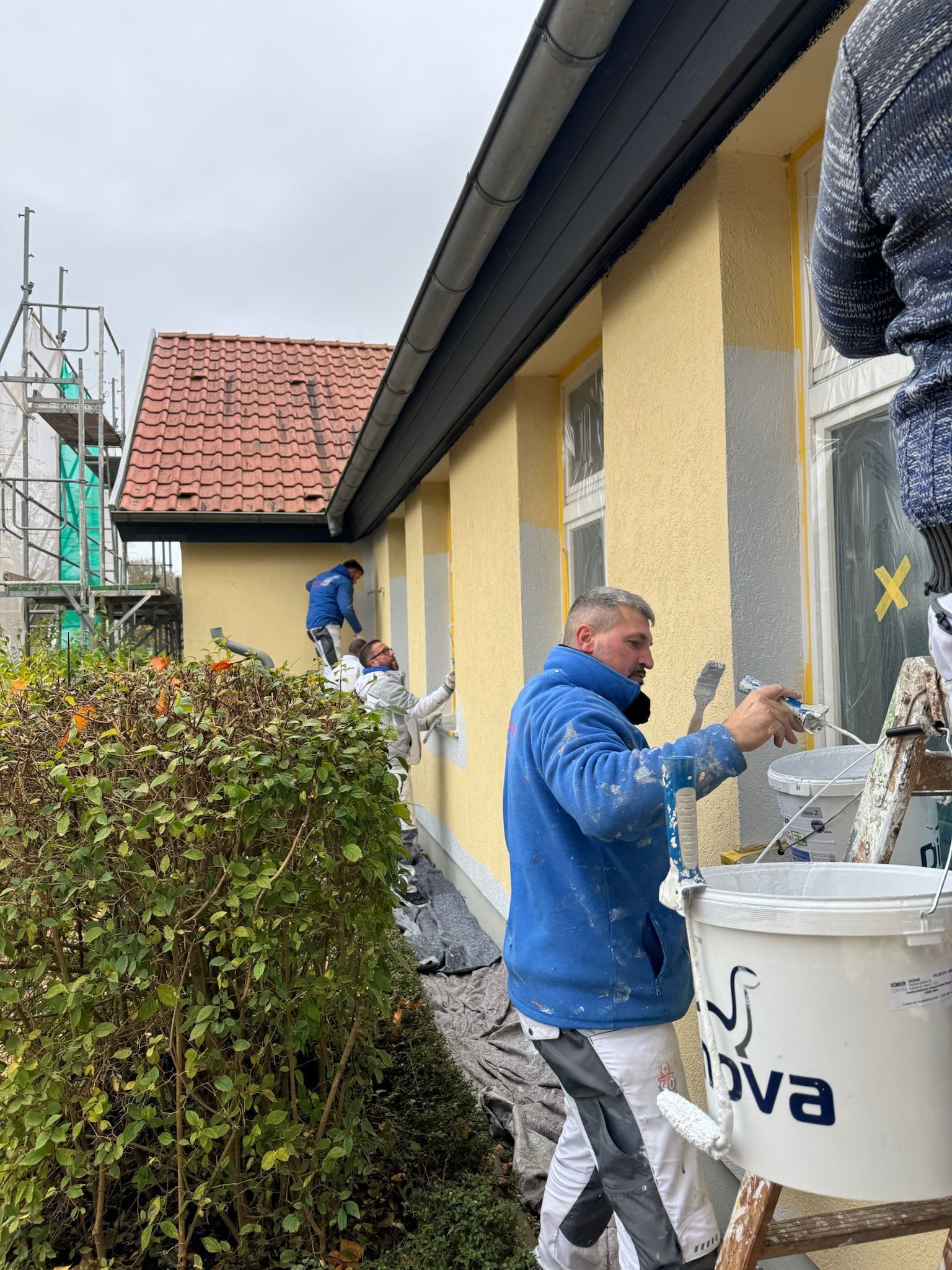 Zwei Männer streichen eine Wand in einem Zimmer.
