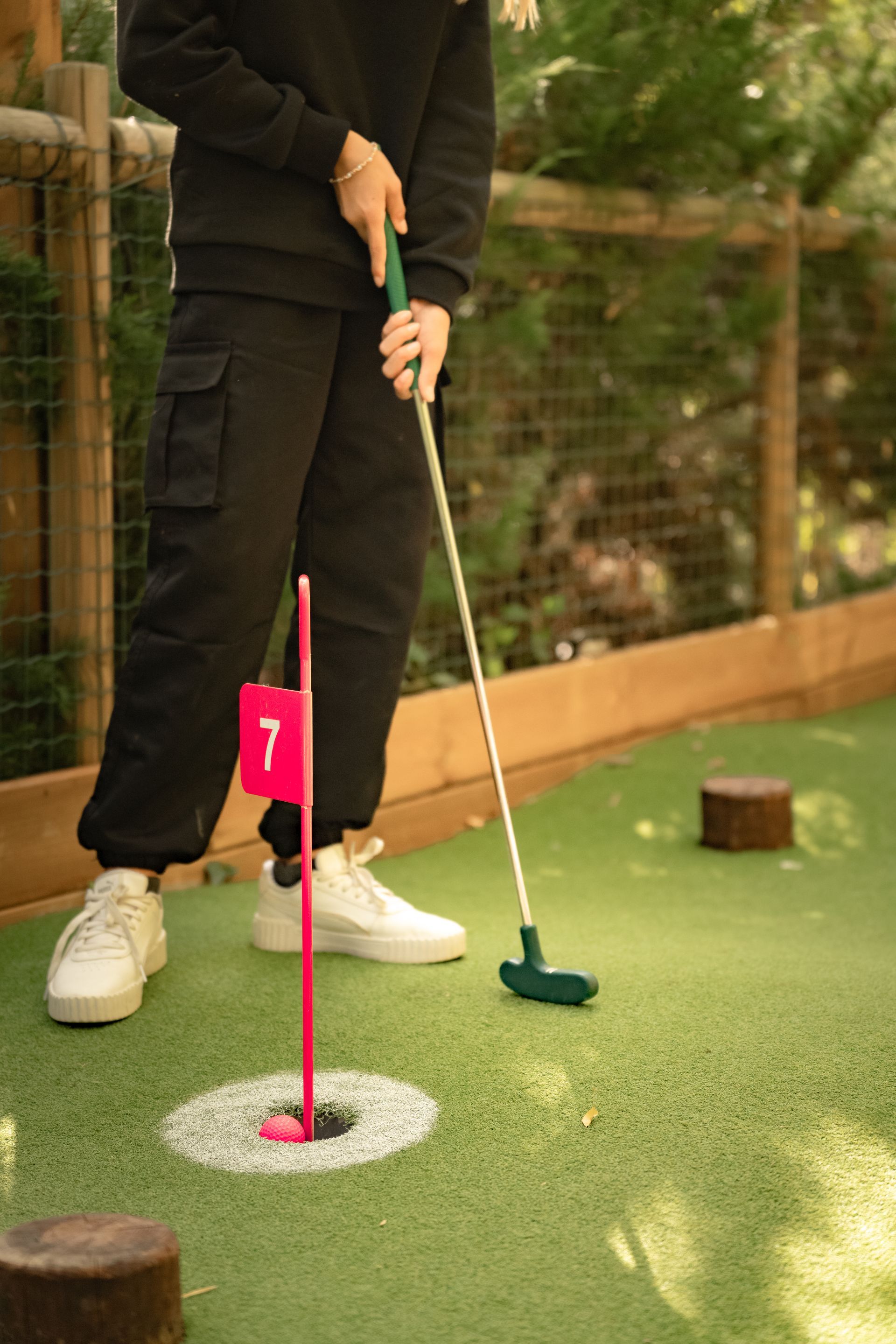Joueur de minigolf, essayant de faire entrer la balle dans un trou signalé par un drapeau rose.