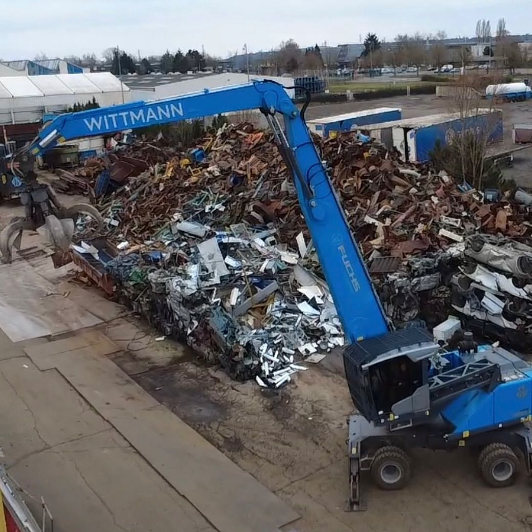 Grue à pince devant un tas de déchets