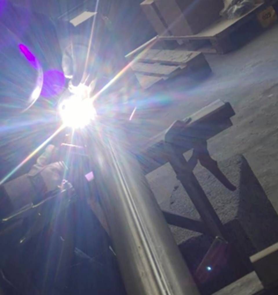 Helle Schweissfunken erleuchten ein Metallrohr. Jemand schweisst in einer industriellen Anlage.