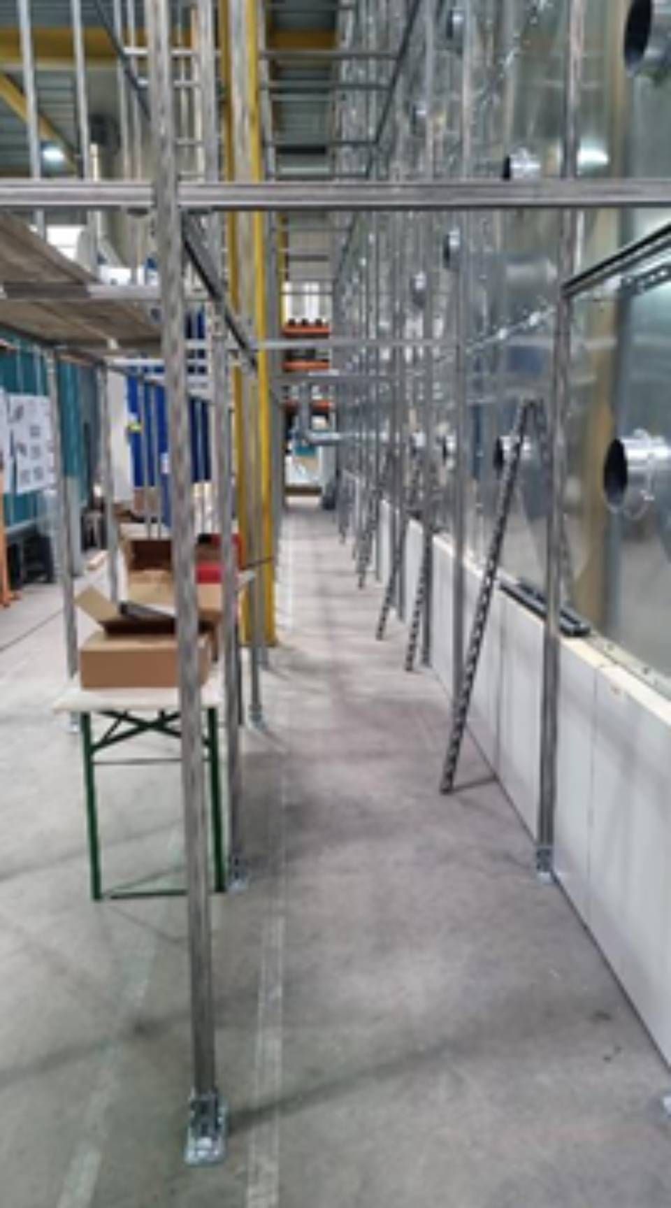 Industrielles Interieur mit Metallrahmen und an der Wand entlang angeordneten Anlagen.