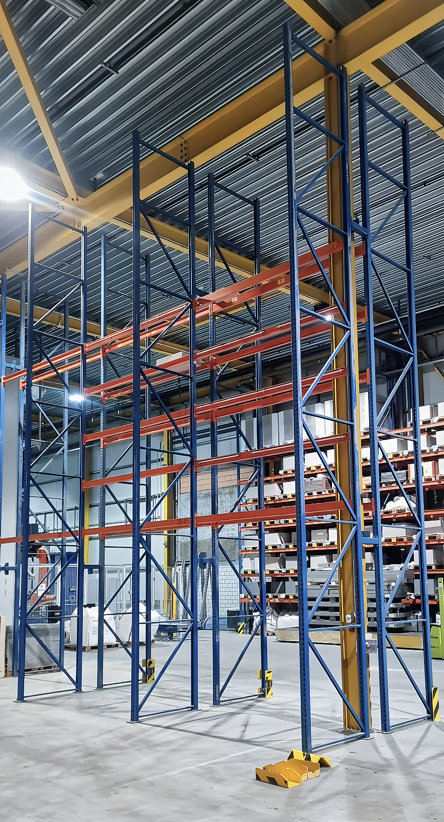 In einer industriellen Umgebung steigt eine Kabelrinne aus Metall empor, im Hintergrund sind blaue Anlagen zu sehen.