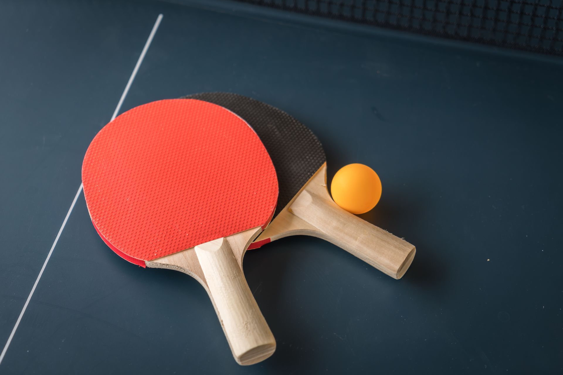 Deux raquettes de ping-pong, l'une à face rouge et l'autre à face noire