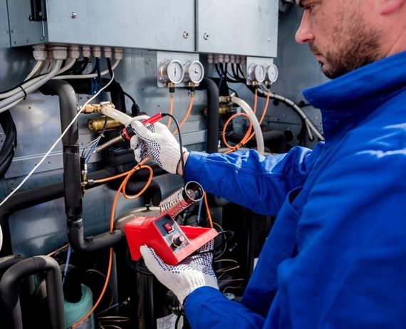 Un hombre con una chaqueta azul está trabajando en una máquina.