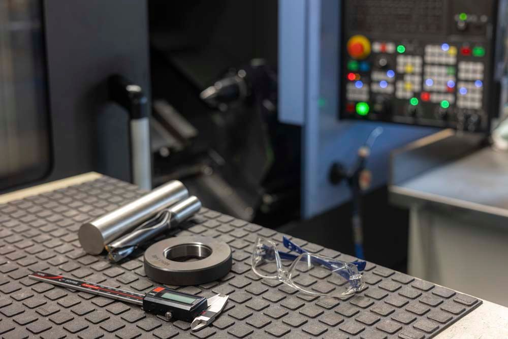 Ein Tisch mit einem Haufen Werkzeug und einer Maschine im Hintergrund.