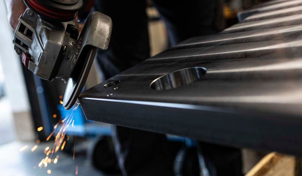 Eine Person schleift ein Stück Metall mit einer Schleifmaschine.