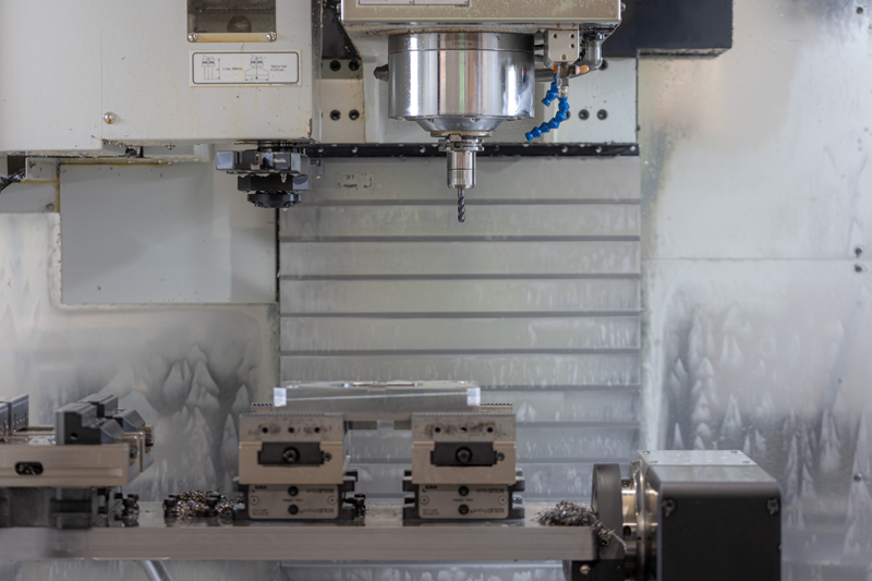 Eine CNC-Maschine schneidet mit einem Bohrer ein Stück Metall.