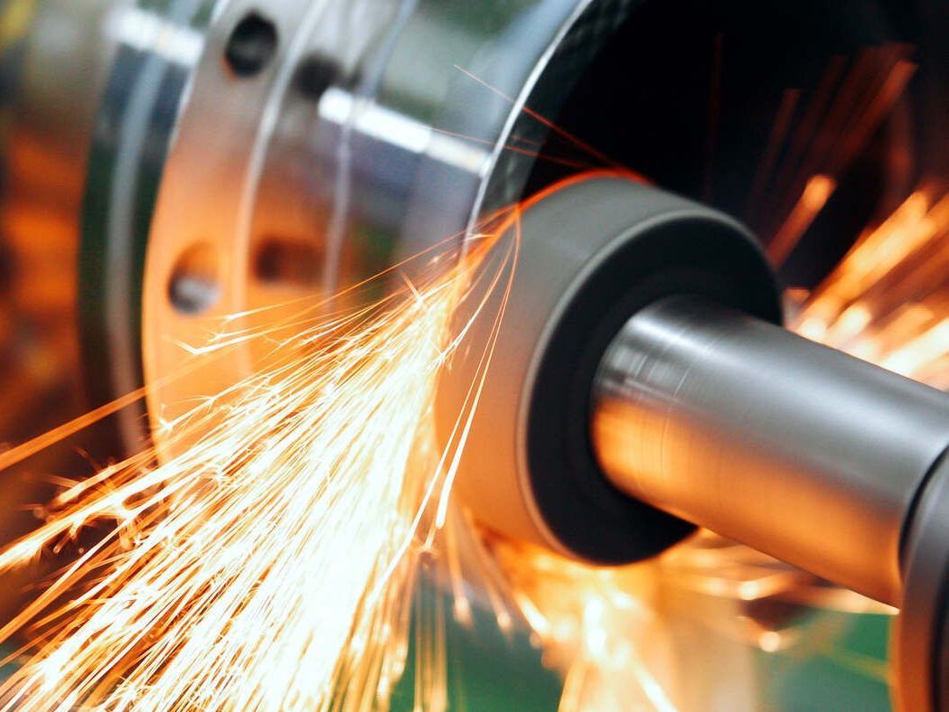 Eine CNC-Maschine schleift ein Stück Metall, wobei Funken austreten.