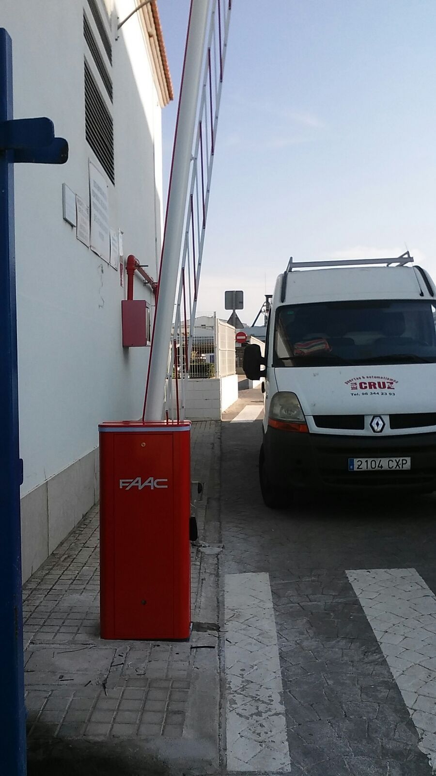 Una furgoneta blanca está estacionada al lado de una barrera roja al costado de la carretera.