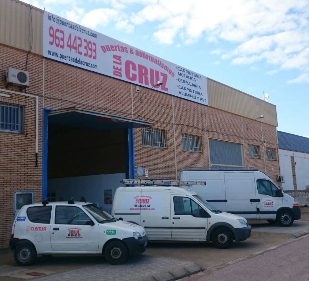 Dos camionetas blancas están estacionadas frente a un edificio que dice cruz