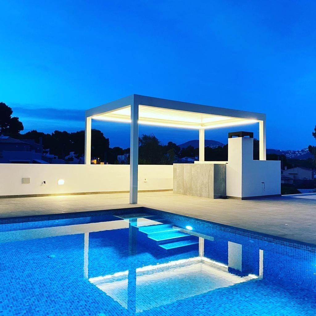 Una piscina con una pérgola encima por la noche.