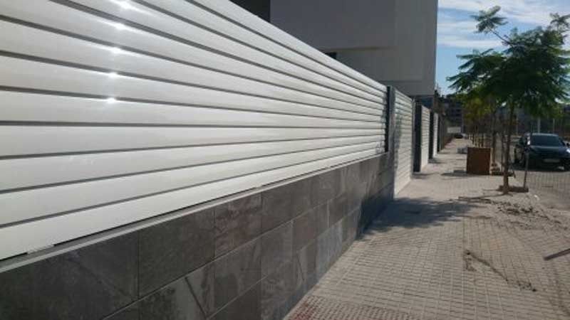 Una valla blanca está a lo largo del costado de un edificio.