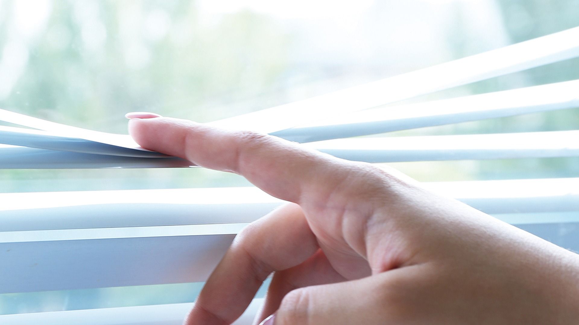 Una persona está abriendo las persianas con el dedo.