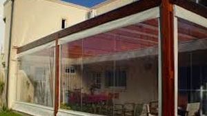 Una casa con pérgola y un patio con muchas ventanas.