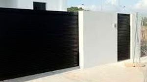 Una valla blanca y negra con dos puertas delante de una casa.