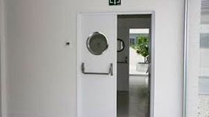 Una puerta blanca con una ventana redonda está abierta a una habitación.