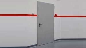 Una puerta gris está colgada en una pared blanca en una habitación.