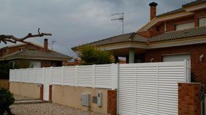 Una valla blanca está delante de una casa de ladrillo.