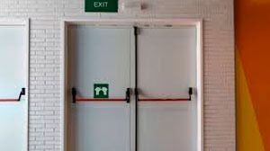 Un par de puertas blancas con un cartel de salida verde en la pared.