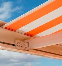 Un primer plano de un toldo de rayas naranjas y blancas contra un cielo azul.