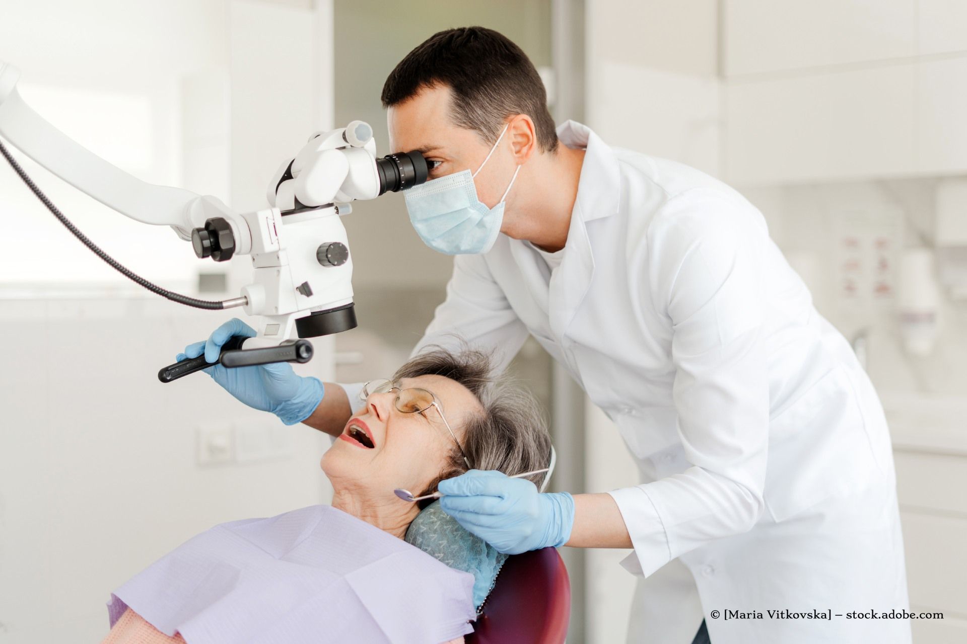 Zahnarzt, der in einer Zahnarztpraxis ein Mikroskop an einem Patienten verwendet.