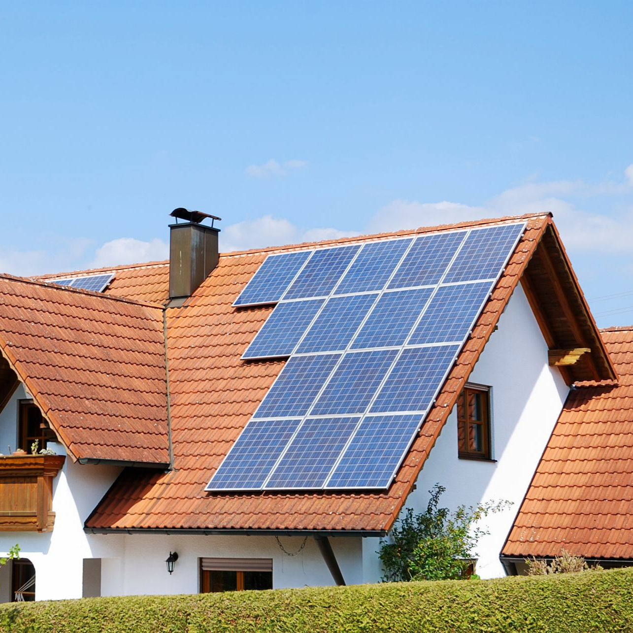 Maison au toit de tuiles rouges et panneaux solaires.