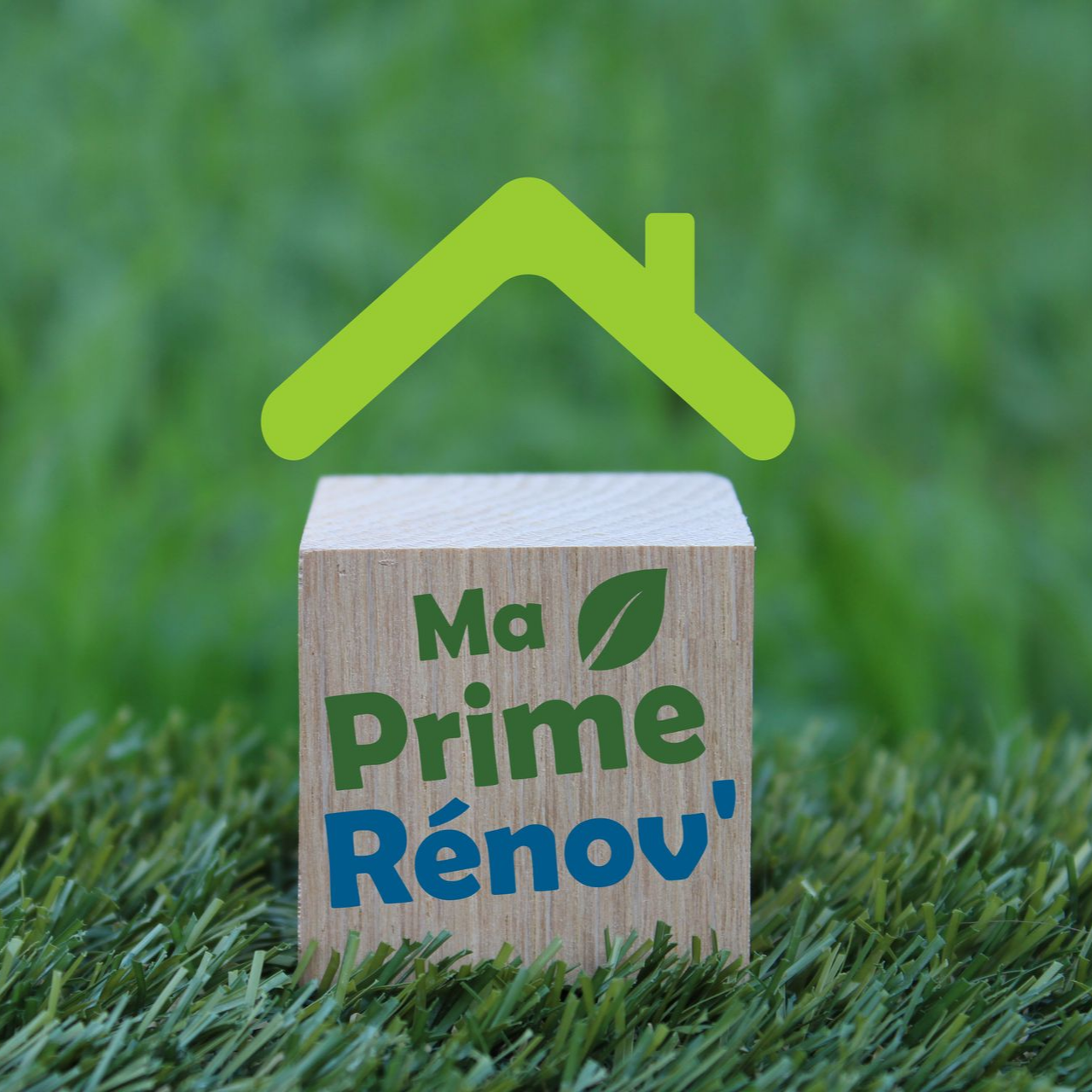 Le logo de MaPrimeRénov sur un petit bloc de maison avec un toit vert, posé sur de l'herbe.
