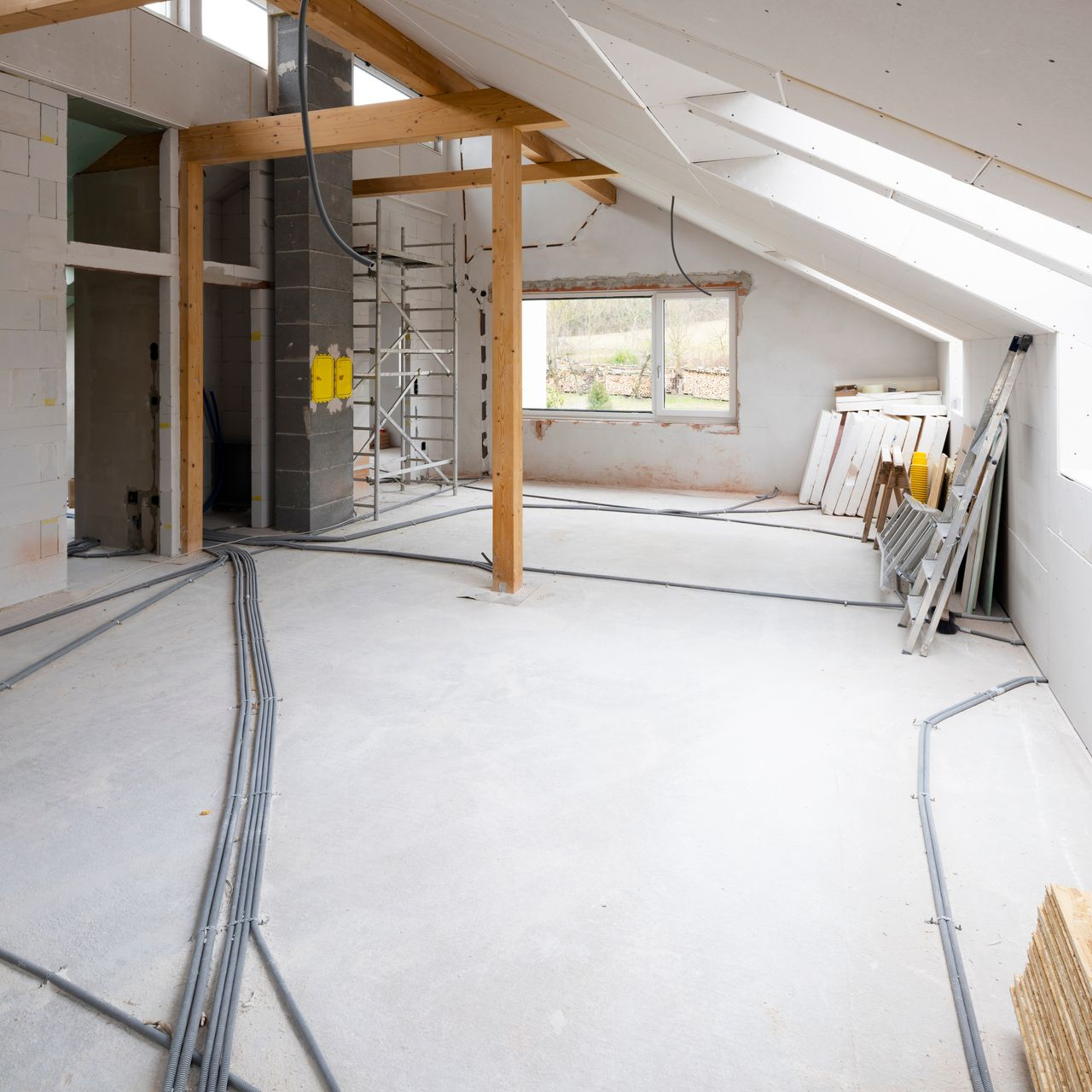 Grenier mansardé en cours de rénovation avec des matériaux de chantier visibles sur le sol.