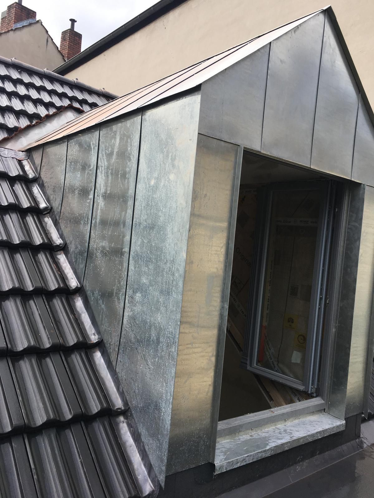 Ein verzinktes Metalldachfenster auf einem Ziegeldach. Das Dachfenster ist für den Fenstereinbau geöffnet.