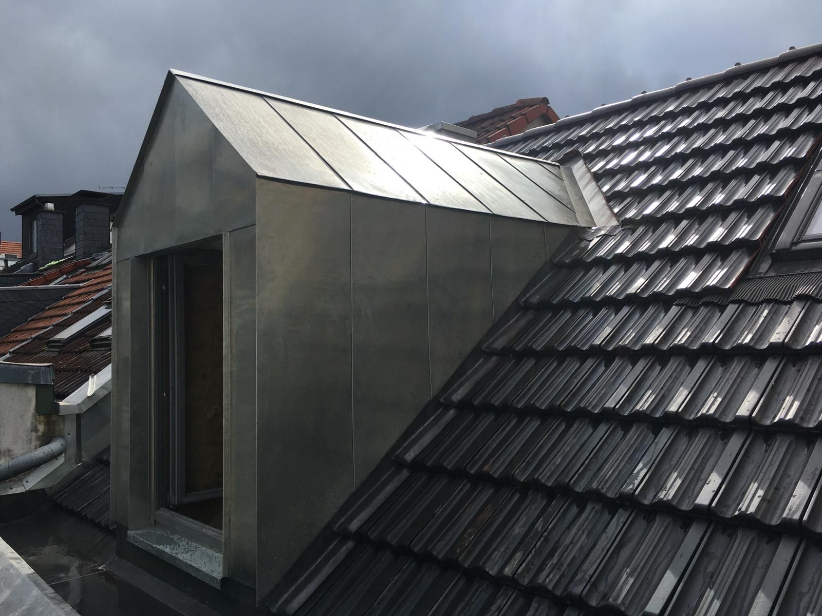 Metallverkleidetes Dachfenster auf einem Ziegeldach, von oben gesehen. Bewölkter Tag.