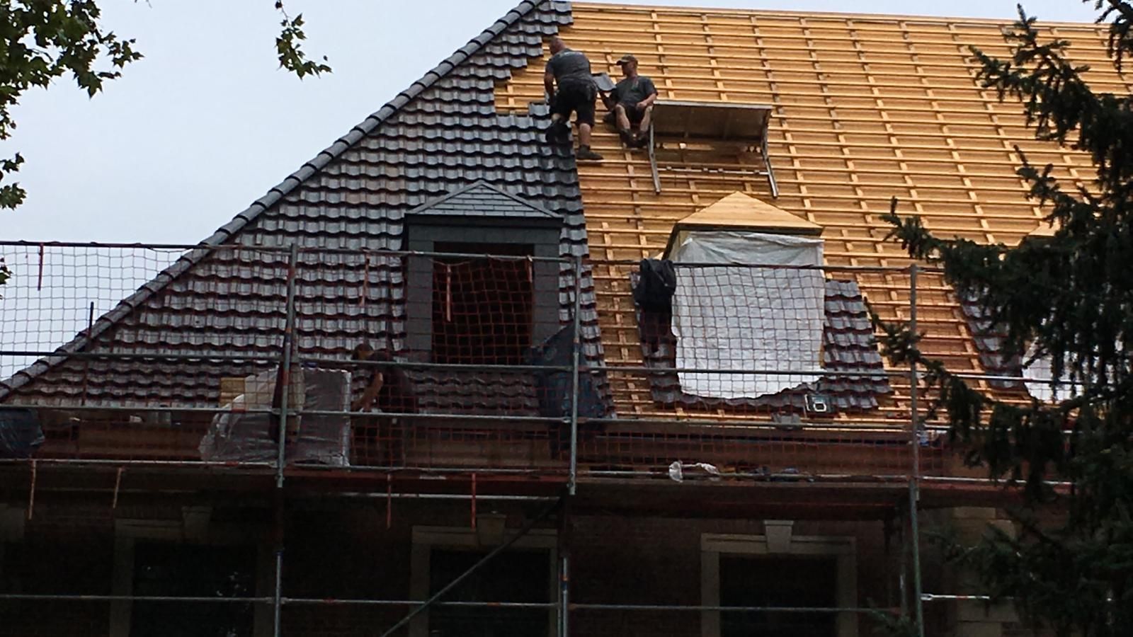 Ein Dachdecker legt Dachziegeln