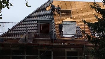 Ein Dachdecker legt Dachziegeln