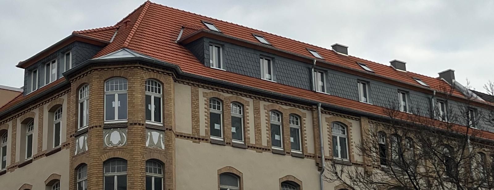 Backsteingebäude mit rotem Ziegeldach und Fenstern. Bewölkter Himmel.