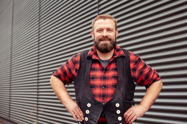 Zwei Dachdecker arbeiten am Dach eines Holzhauses