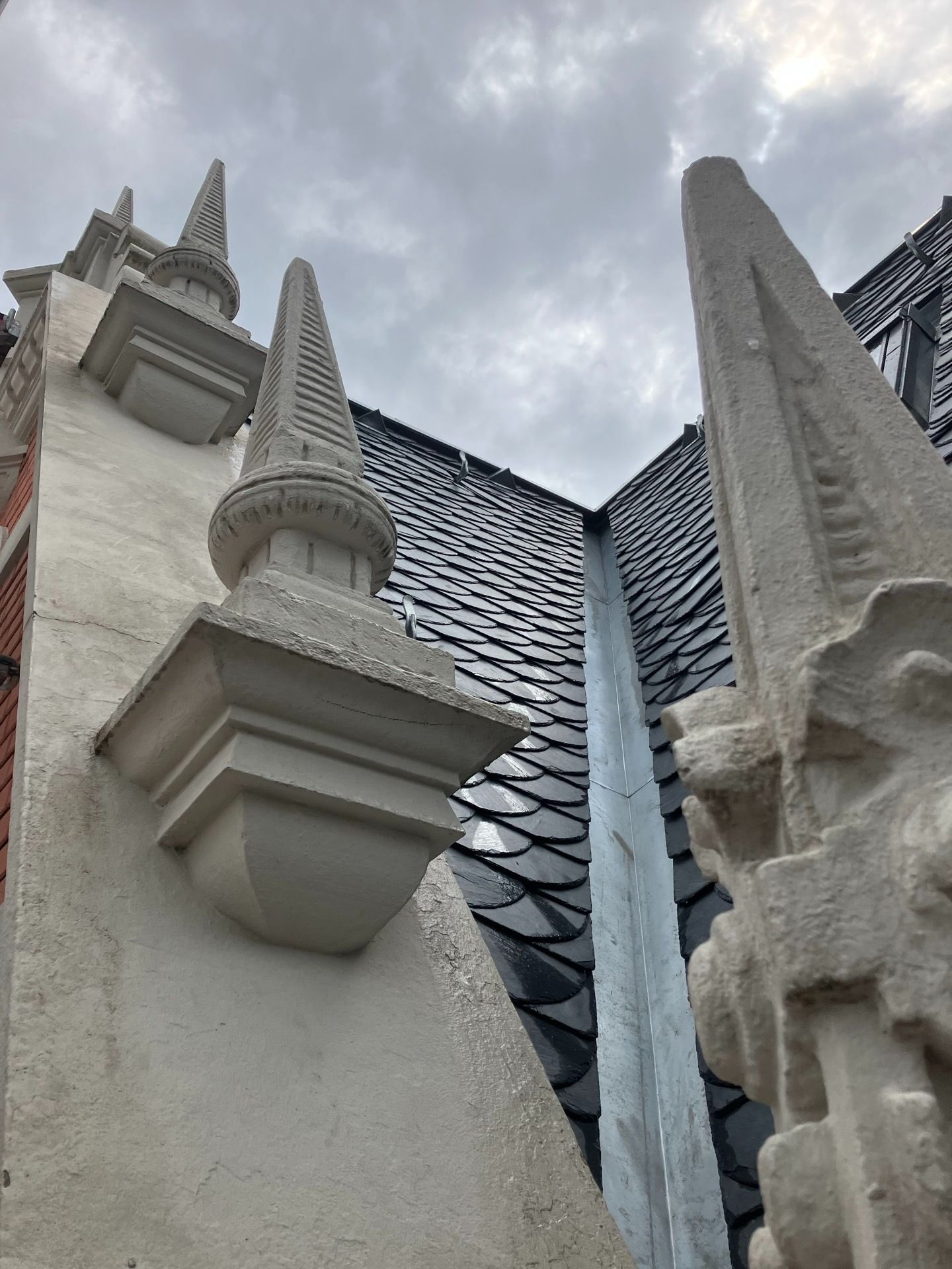 Architektonische Details, Steintürme und dekoratives Dach vor bewölktem Himmel.